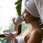 A woman with a towel on her head drinking from a mug as part of her morning routine for anxiety.